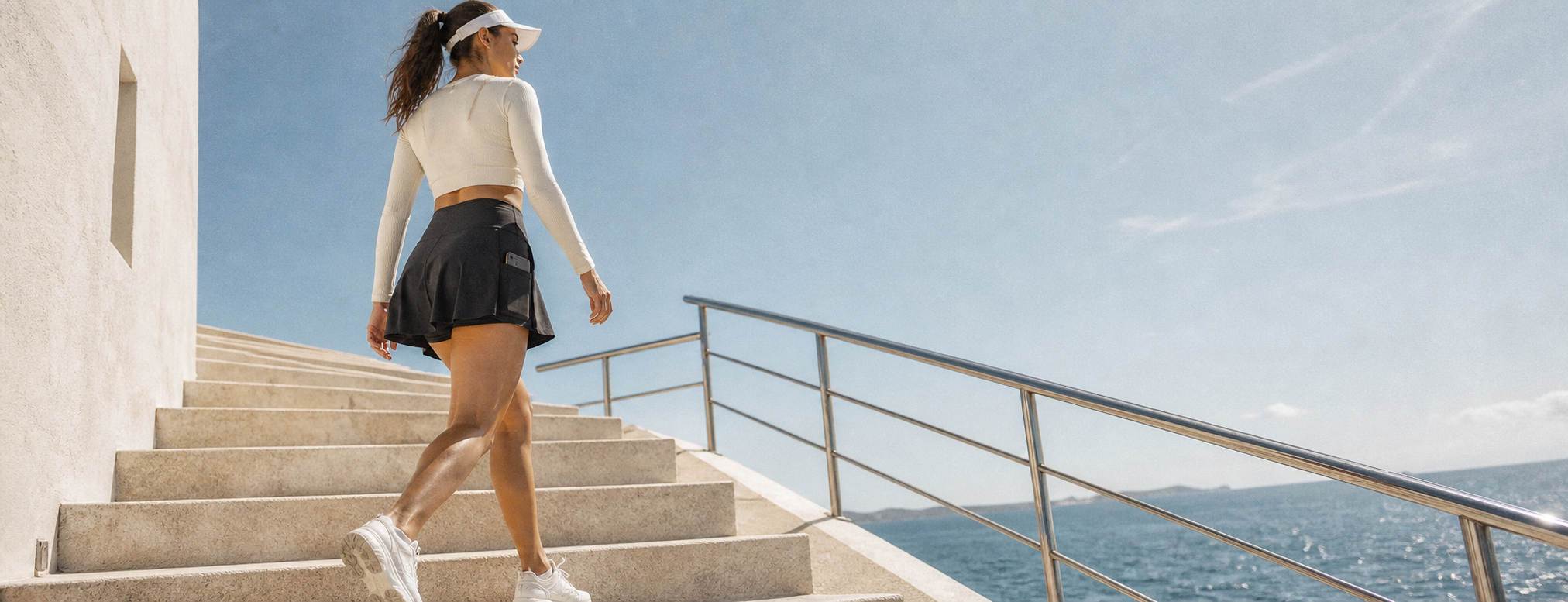 Woman walking in a black Aelvoro performance skort on sunlit coastal steps